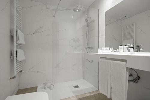 a white bathroom with a shower and a sink at Hotel Zentral Ramiro I Oviedo in Oviedo