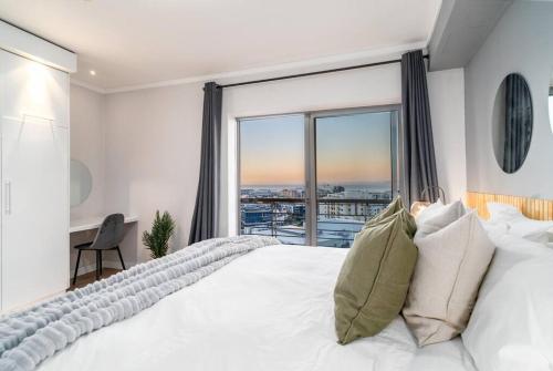 a bedroom with a white bed and a large window at Cozy Ocean View Apartment in Cape Town