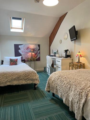 a bedroom with two beds and a desk at The Crown Lodge & Restaurant in Dogdyke
