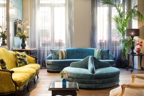 a living room with a blue couch and yellow chairs at Castille Paris – Starhotels Collezione in Paris