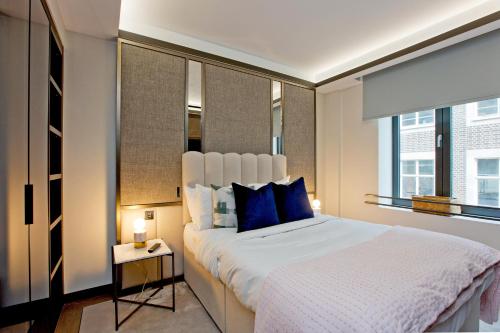 a bedroom with a large bed with blue pillows at 37GS Residences in London