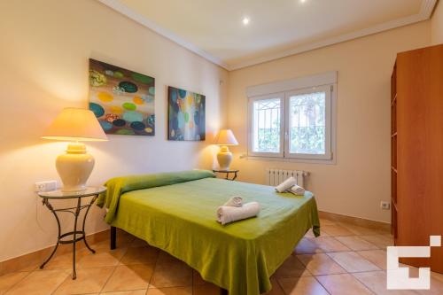 a bedroom with a green bed with two towels on it at Villa Coral - Grupo Turis in Calpe