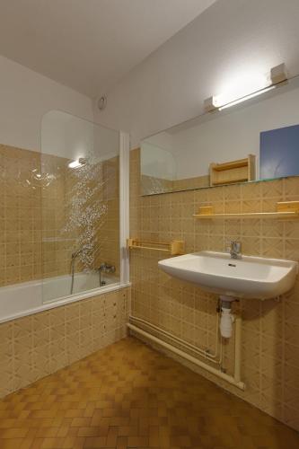 une salle de bain avec un lavabo et une baignoire dans l'établissement Vacancéole - Résidence Cabourg, à Mont-de-Lans