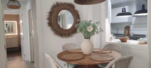 une table à manger avec un vase de fleurs et un miroir dans l'établissement Kentia golf Playa Granada, à Motril