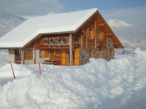 Cette cabane en rondins dispose d'un balcon dans la neige. dans l'établissement Les Chalets du Choumeau, à Saint-Léger-les-Mélèzes