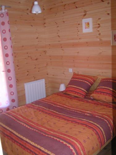 - une chambre avec un lit dans une pièce dotée de murs en bois dans l'établissement Les Chalets du Choumeau, à Saint-Léger-les-Mélèzes