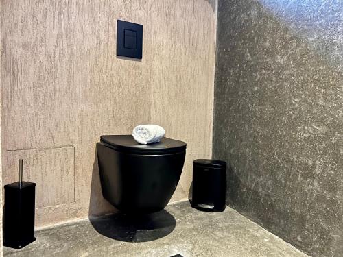 a bathroom with a black toilet and two trash cans at Psamathi Living & Taste in Marathi