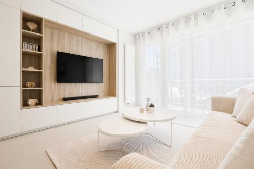 uma sala de estar branca com uma televisão e uma mesa em SANTA MONICA Parking gratuit em Annecy