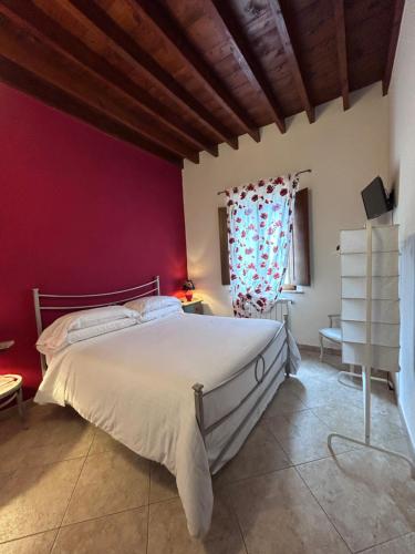 1 dormitorio con cama blanca y pared roja en Valdorcia Belvedere b&b, en Pienza