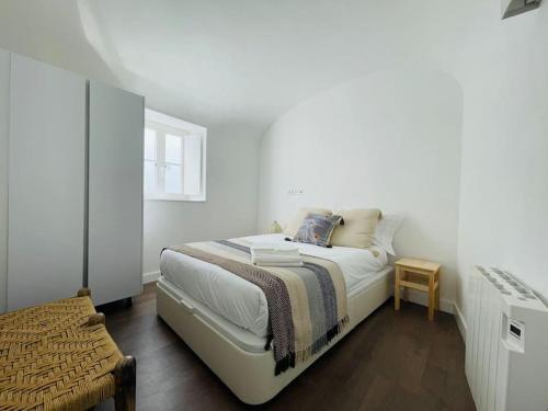 a white bedroom with a bed and a window at Casa da Travessa in Évora
