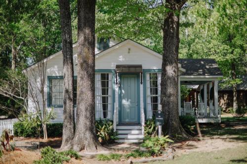 a small house with a blue door and trees at The Myrtles in Saint Francisville