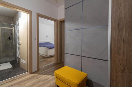 łazienka z żółtym stołkiem i sypialnia w obiekcie LENIJE w mieście Vinkovci