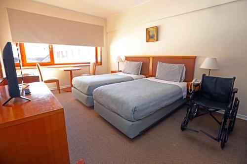 a hotel room with two beds and a desk and a television at Gran Hotel Vicente Costanera in Puerto Montt