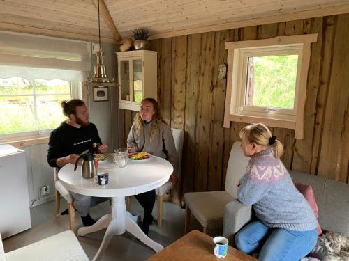un grupo de personas sentadas alrededor de una mesa en una habitación en Modern turf house, en Kokelv