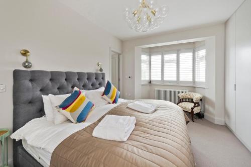 a bedroom with a large bed with a large headboard at Wonderful family home with garden near Twickenham by UnderTheDoormat in London
