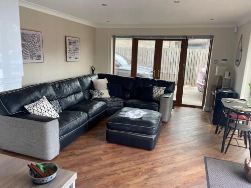 a living room with a black leather couch at Prancing Horse Cottage in Sabden