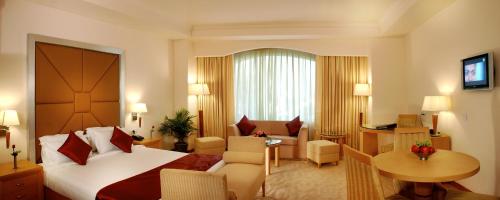 ジャンムーにあるInn Riviera Jammuのベッドとリビングルームが備わるホテルルームです。