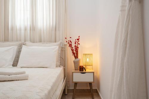 a white bedroom with a bed and a vase on a night stand at Orkos Naxian Wave 3 in Mikri Vigla