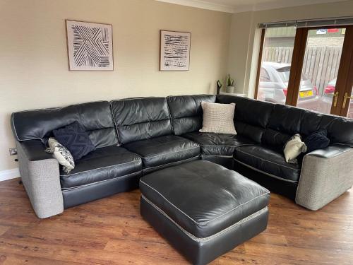 a black leather couch in a living room at Prancing Horse Cottage in Sabden
