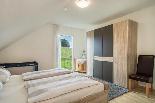 a bedroom with a bed and a chair and a window at Haus Barbara, Ferienwohnung, 90qm in Unterreitnau
