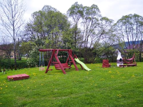 un parque infantil con columpios en un campo en Domek nad Olszanka, en Olszanica