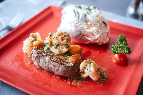 a red plate with a piece of meat with shrimp at Der Postwirt in Söll