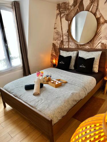 1 dormitorio con 1 cama grande y espejo en la pared en Studio Exotique Hyper-Centre Enghien 12min Paris en Enghien-les-Bains