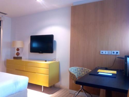a bedroom with a bed and a desk with a tv at Hotel Alfonso in Zaragoza