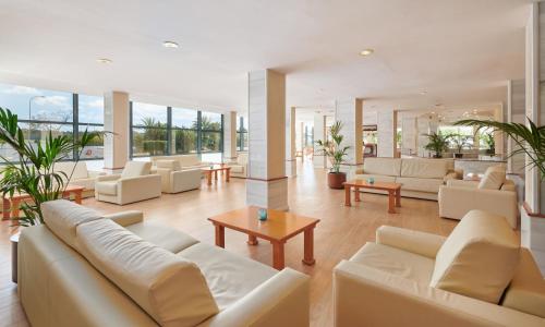 una sala de estar con muebles blancos y ventanas grandes. en Grupotel Taurus Park en Playa de Palma