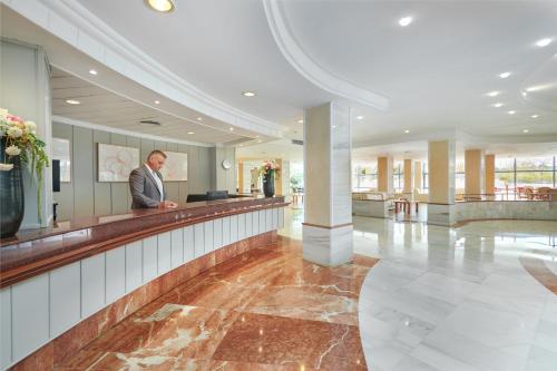 a man standing at a reception counter in a lobby at Grupotel Taurus Park in Playa de Palma