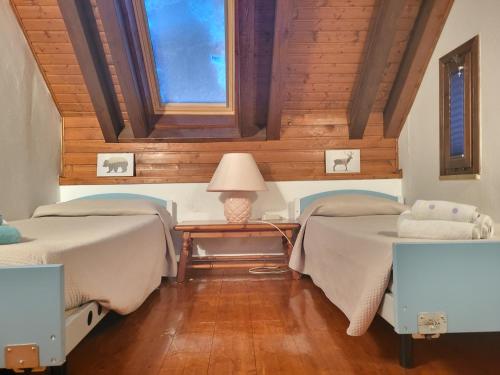 um quarto com 2 camas e uma mesa com um candeeiro em La casa lassù em Tarvisio