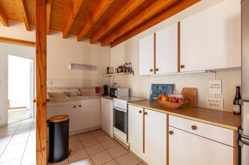 une cuisine avec des armoires blanches et un plafond en bois dans l'établissement La Grange - Charmante maison à Langrune-sur-mer, à Langrune-sur-Mer