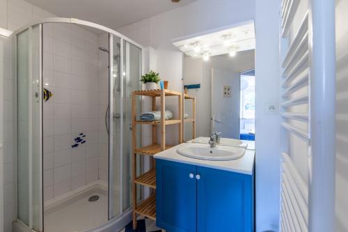 W łazience znajduje się niebieska umywalka i prysznic. w obiekcie La Grange - Charmante maison à Langrune-sur-mer w mieście Langrune-sur-Mer