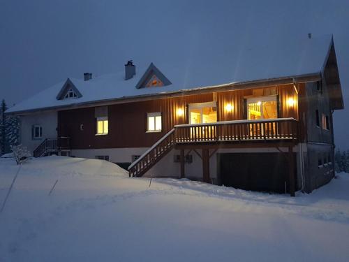 a house with a deck in the snow at Chambre d'hôtes LES BRIMBELLES in Gérardmer