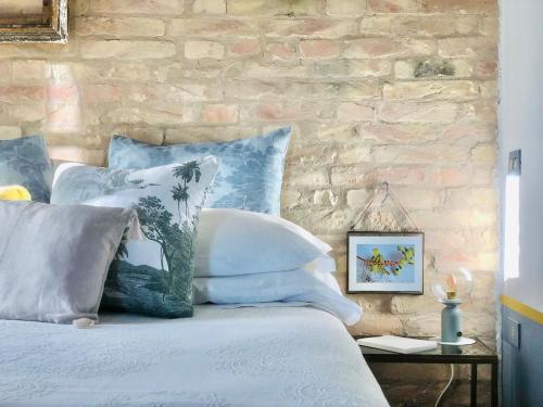 a bed with blue and white pillows and a brick wall at Effimera - Relaxing Retreat in Citta' Sant'Angelo
