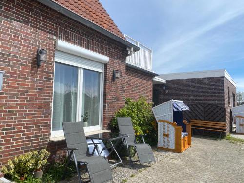 a patio with a table and chairs next to a building at FRIESENHÜTTE NORDDEICH in Norddeich