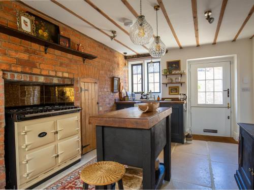 Little Oakley Cottage في Sandford Saint Martin: مطبخ مع جزيرة في جدار من الطوب