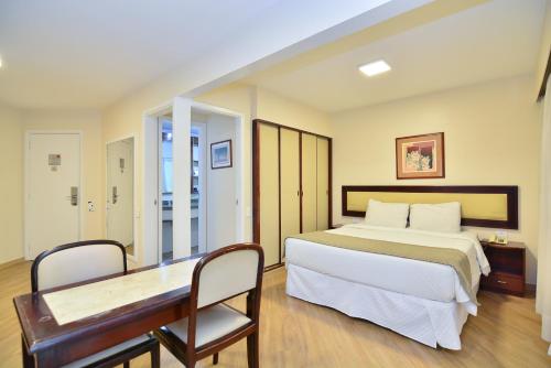 - une chambre avec un grand lit et un bureau dans l'établissement H4 Fortune Jardins, à São Paulo