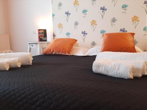Una cama con almohadas naranjas y blancas. en B&B La Jacaranda affittacamere en SantʼAntìoco