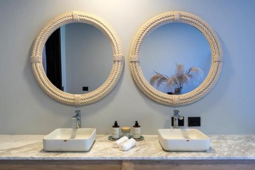 a bathroom with two sinks and two mirrors at Tau House in Guatapé