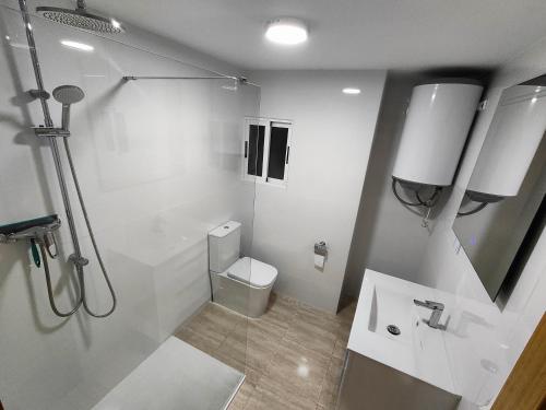 a white bathroom with a toilet and a sink at Sea view apartment in Cullera