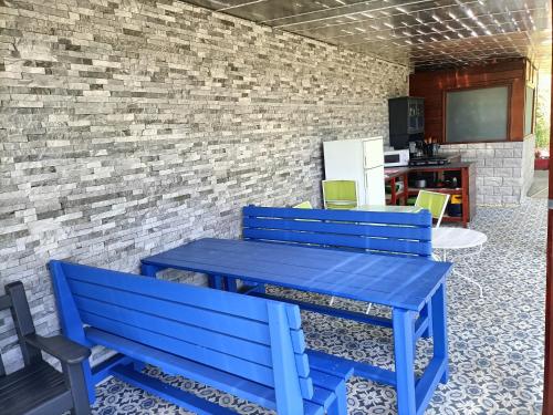 einem blauen Tisch und zwei Bänken vor einer Ziegelmauer in der Unterkunft Cabane Dans Les Arbres - Les Lutins in Mechmont