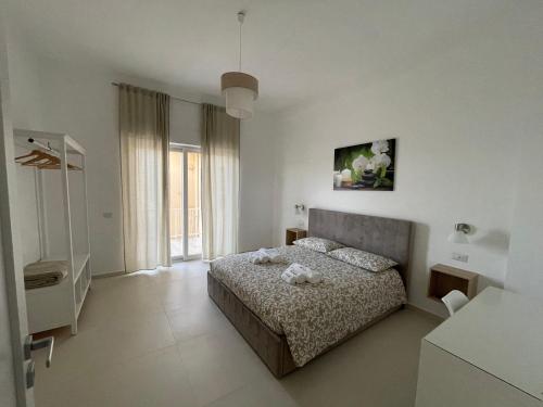 a white bedroom with a bed and a window at Casa Langellotti plus in Naples