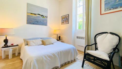 une chambre blanche avec un lit et une chaise dans l'établissement jolie maison de vacances a proximitée du port et des commerces et de la plage, à La Flotte