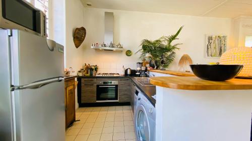 une cuisine avec un réfrigérateur et un lave-vaisselle dans l'établissement jolie maison de vacances a proximitée du port et des commerces et de la plage, à La Flotte