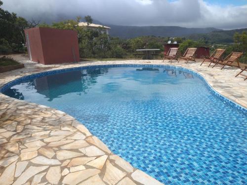 a large swimming pool with chairs and a table at Aldeia da Serra Lapinha in Santana do Riacho