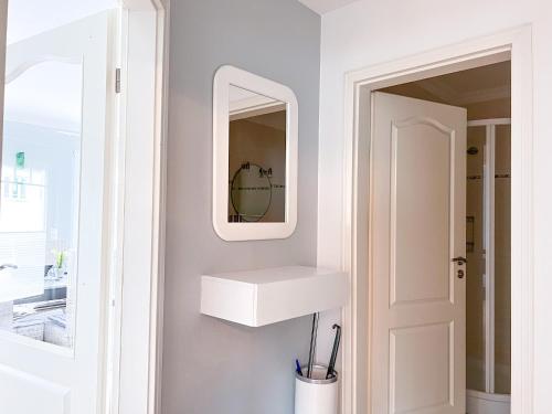 La salle de bains est pourvue d'un lavabo blanc et d'un miroir. dans l'établissement Haus Elaine App. 19, à Westerland