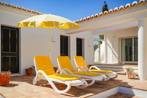 a group of chairs and an umbrella on a patio at Casa Igreja in Carvoeiro