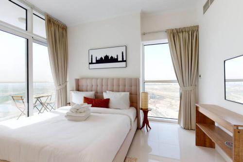 a white bedroom with a large bed and large windows at Key View - Carson A, DAMAC Hills in Dubai Marina