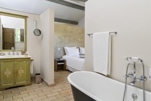 1 dormitorio con 1 cama y baño con bañera. en Coquillade Provence en Gargas